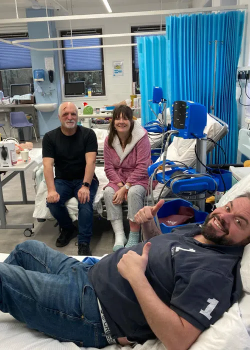 Three service users are taking part in a nursing simulation, a man is lying on a bed
