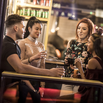 A group of students are in a modern bar, smiling and chatting to each other