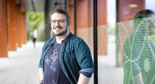 A male wearing casual clothing is standing outside the Catalyst building, smiling