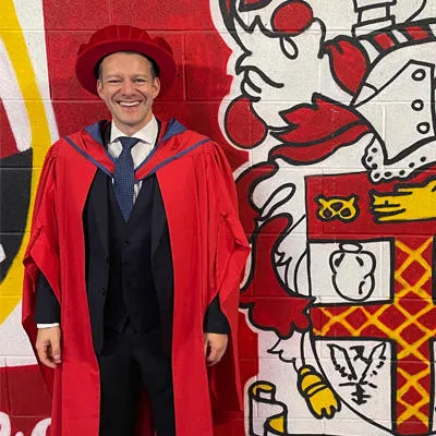 Andrew wearing red cap and gown at graduation