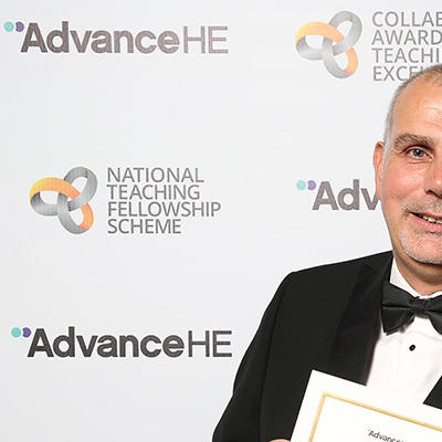 Ian Davies in a tuxedo holding a certificate