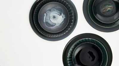 Three dark ceramic bowls with swirling grey and white centres arranged on a pale surface.