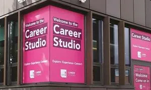 Campus windows wrapped in magenta signs reading 'Welcome to the Career Studio.'