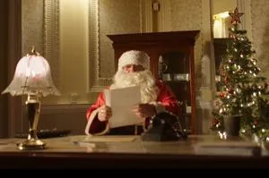 Santa sat at a desk reading a child's letter