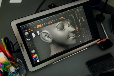 Tablet displays a detailed grey 3D model of a human head in sculpting software.