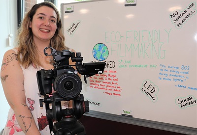 Film Production student Rebecca Head holding a camera in front of a whiteboard