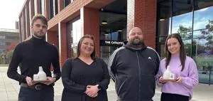 Four people stood outside the Catalyst building - two of which are holding awards