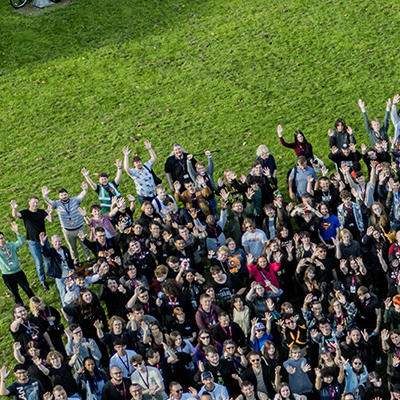An aerial photo of a large group of people with their hands in the air
