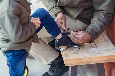Adult tying up the shoelace of a small child