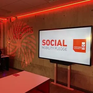 Screen in an esports room displays the words 'Social Mobility Pledge.'