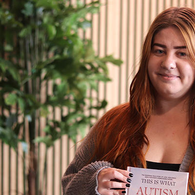 A women with long red hair smiling and holding a book