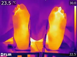 Thermal image of two feet with bright yellow soles and a temperature scale from 22.5 to 30°C.