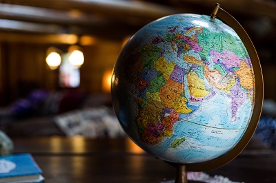 Colourful world globe stands on a table in a softly lit room.