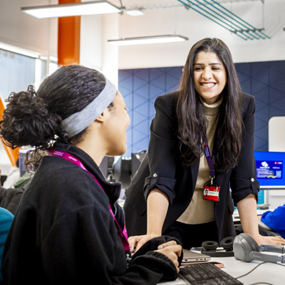 Two females are chatting and working in the modern computer lab