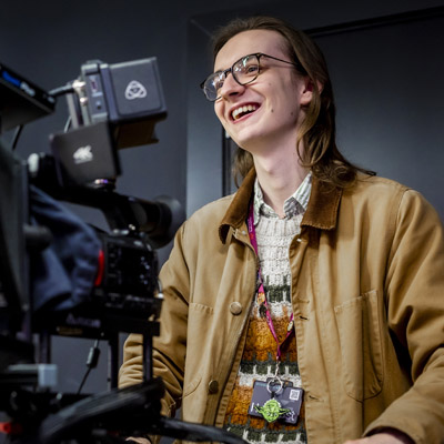 A casually dressed male student is using the broadcasting camera equipment