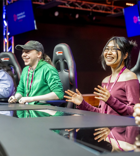 Young students casually dressed are sitting at the games broadcasting panel chatting and smiling